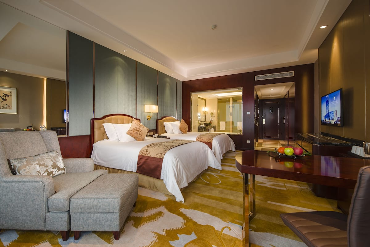A hotel room with a large bed, a sofa, a small table, and a TV.