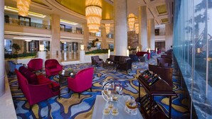 A spacious lobby with a patterned carpet, multiple seating areas, and large chandeliers.