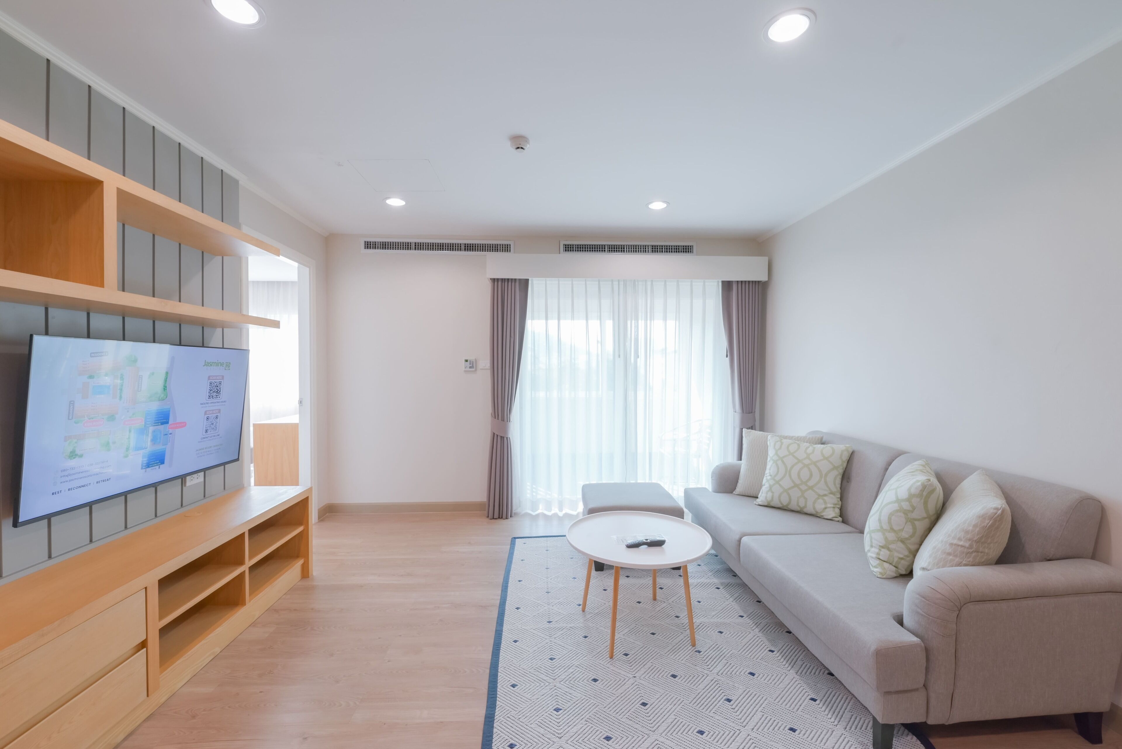 Una sala de estar moderna con una televisión de pantalla plana, un sofá, una mesa de centro y un tapete estampado.