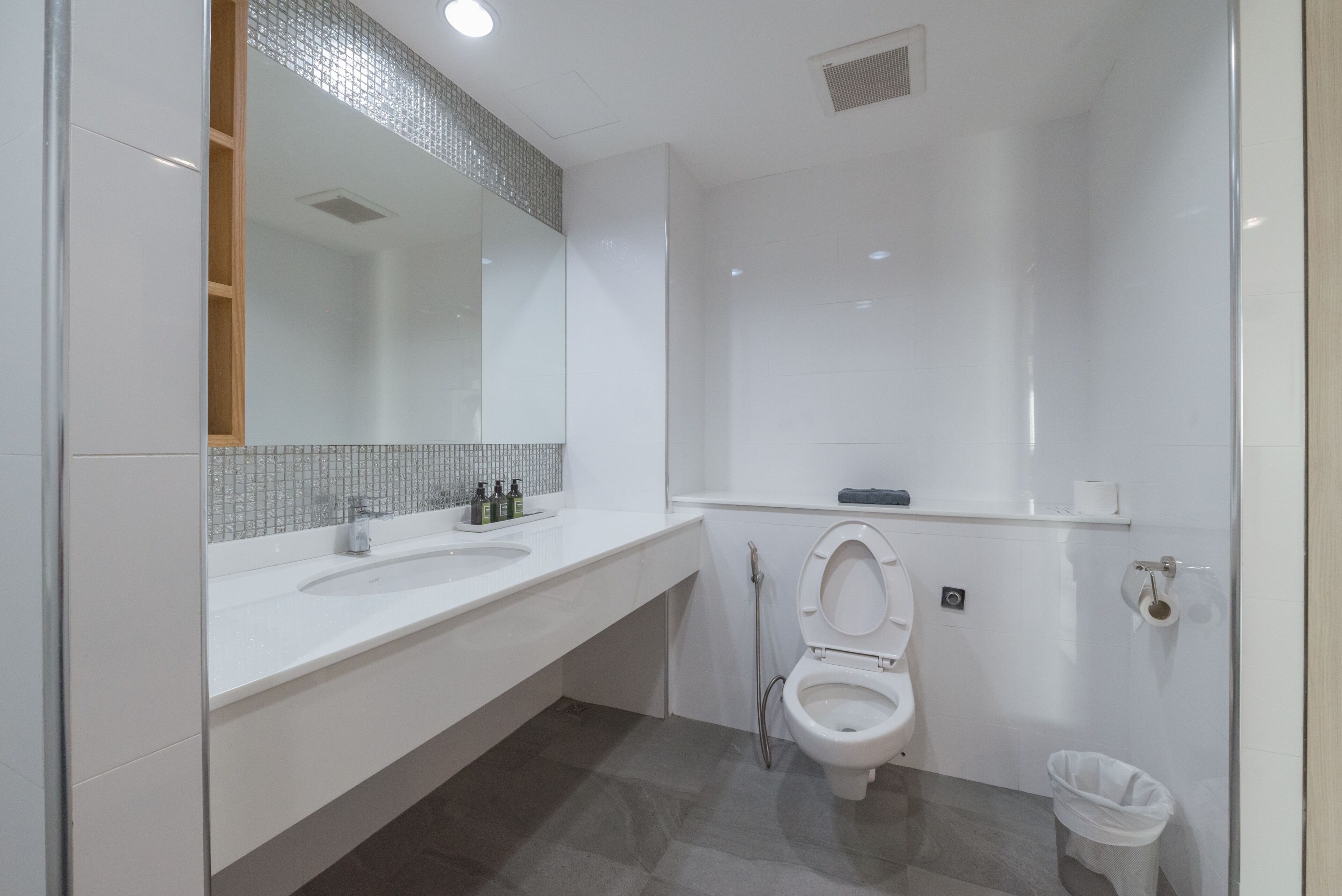 A modern bathroom with a white sink, mirror, and toilet.