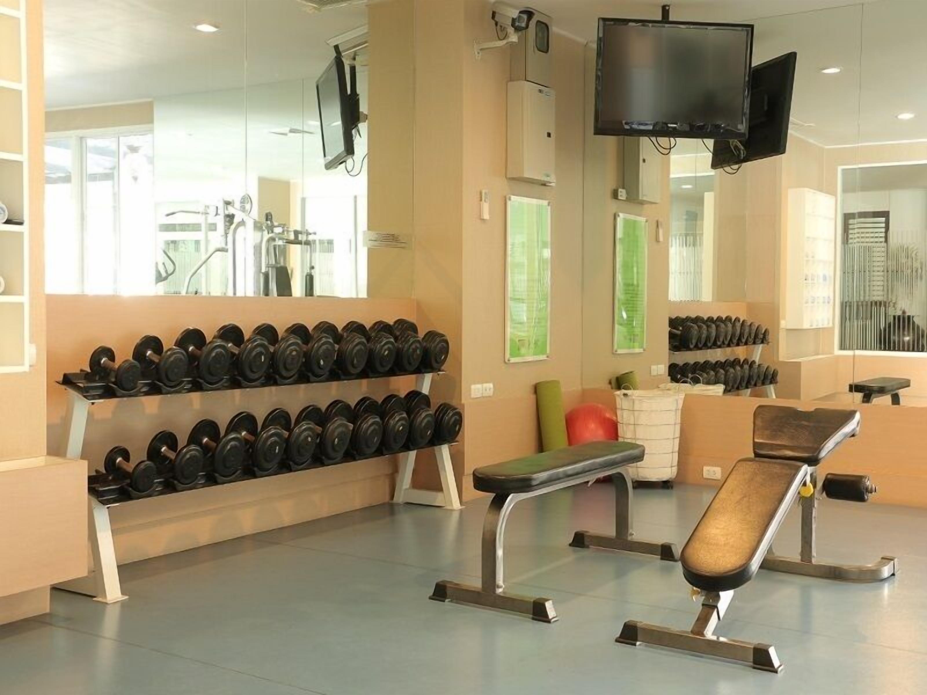 A gym with weight racks, a bench, and mirrors.