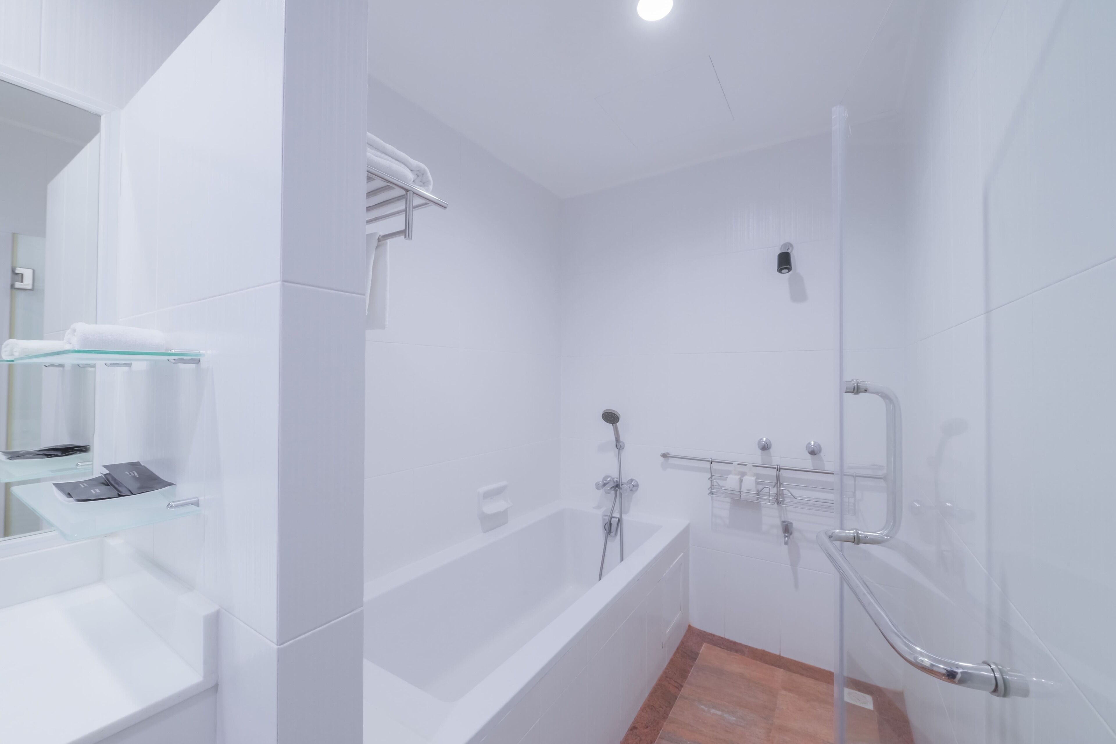 A modern bathroom with a glass shower enclosure, a white sink, and a mirror.