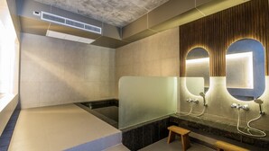 Une salle de bain moderne dotée d’une douche à parois de verre, d’un banc en bois et d’un grand miroir avec un cadre en bois.