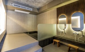 A modern bathroom with a glass-enclosed shower, a wooden bench, and a large mirror with a wooden frame. - Jasmine Resort Sriracha (Si Racha)