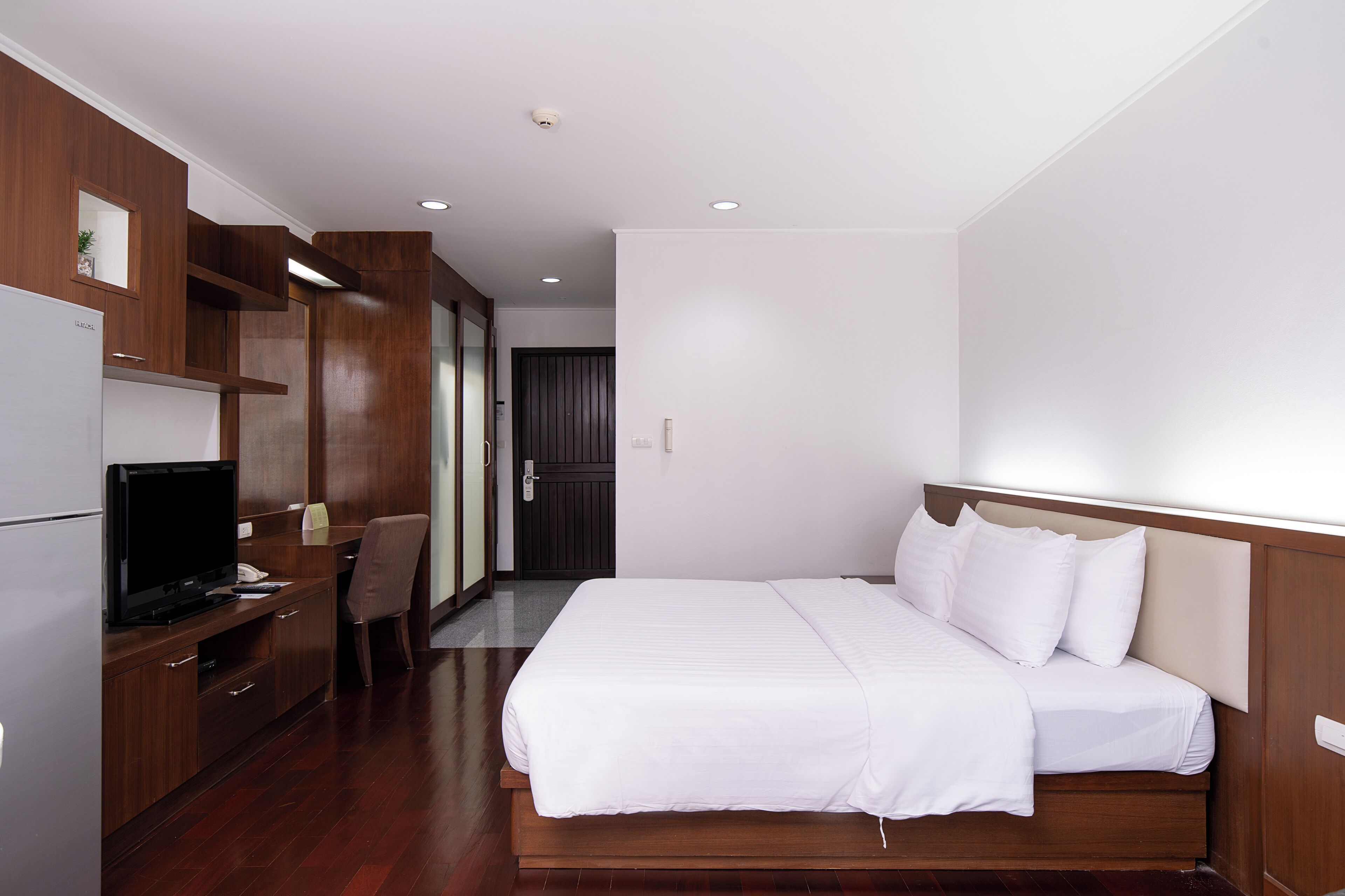 Una habitación de hotel con una cama, un escritorio con televisor y una silla.