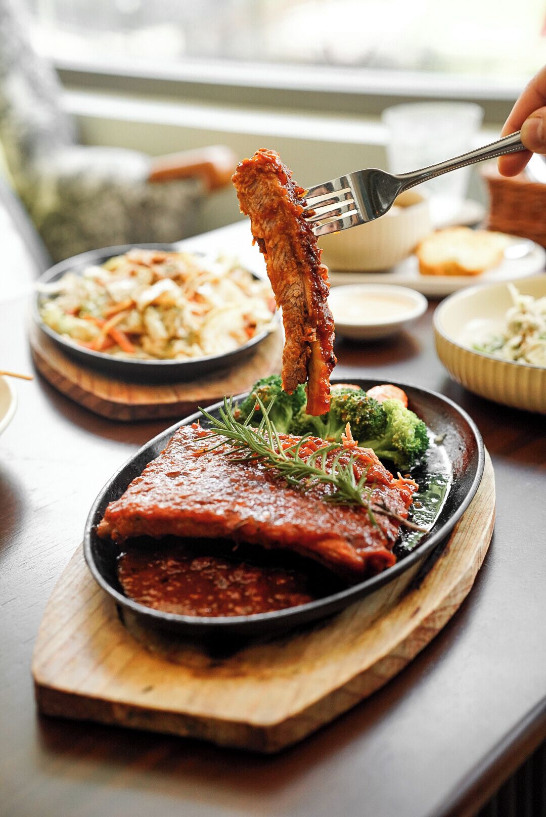 A dish of meat with sauce and broccoli on a wooden board.