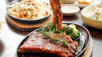 A dish of meat with sauce and broccoli on a wooden board.