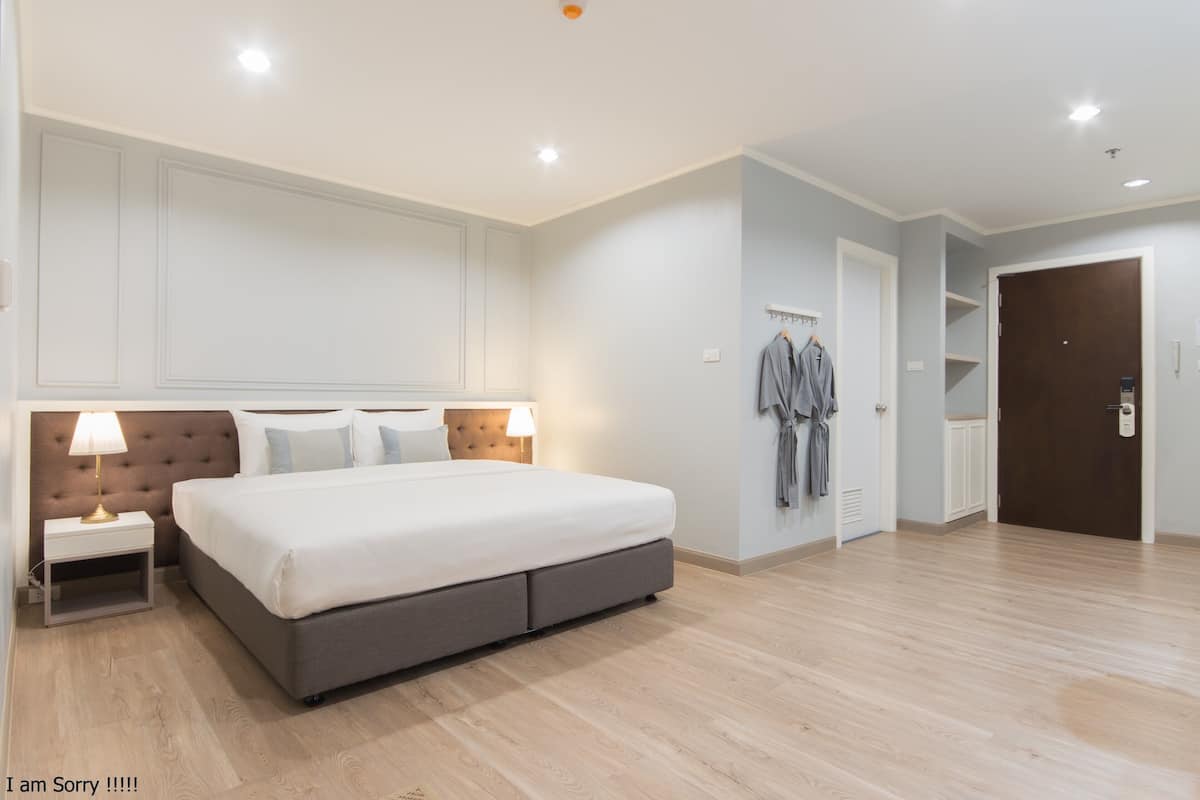 Un dormitorio amplio con una cama grande, mesitas de noche, un armario y una puerta que da a otra habitación.