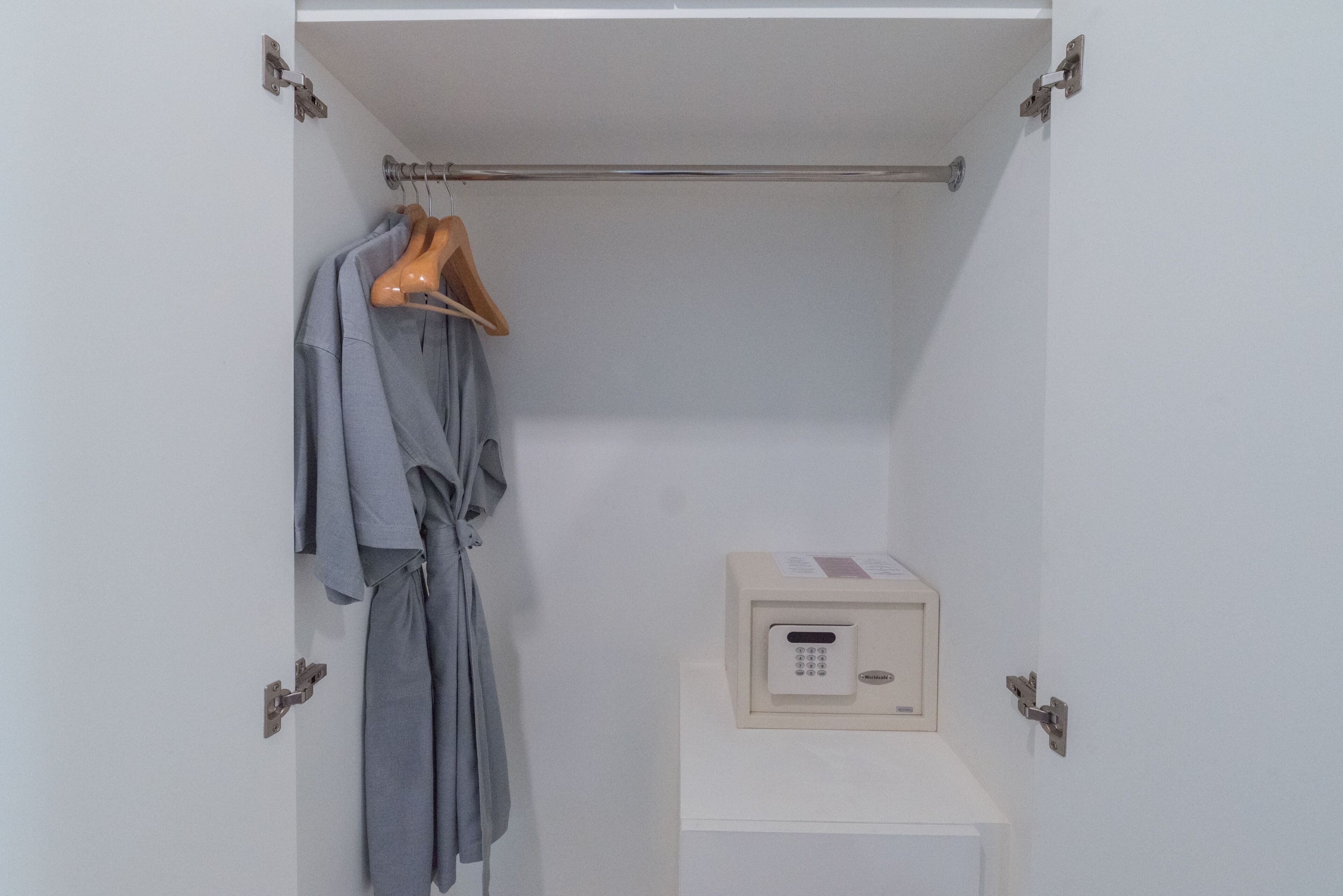 A closet with a hanging rack, a robe, and a small box with a lock.