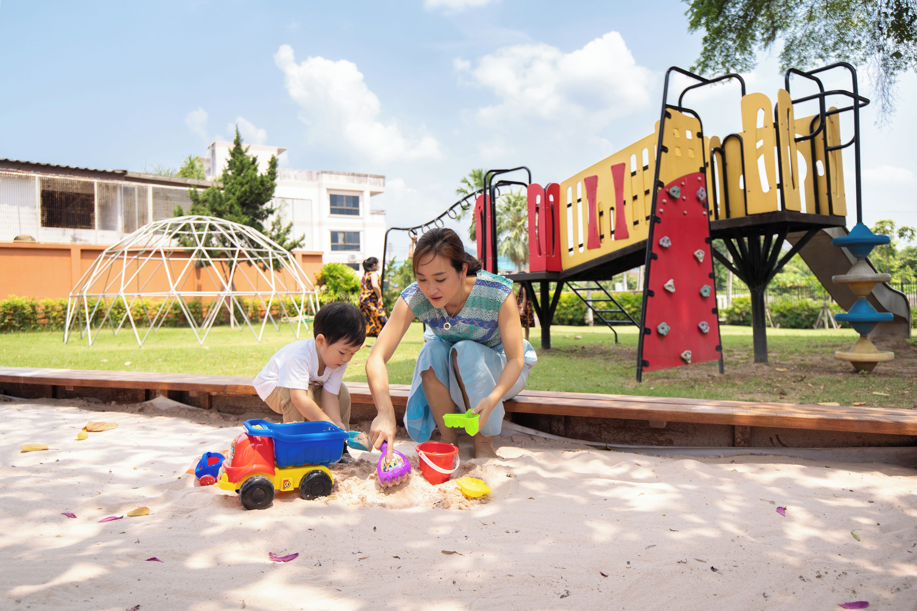 A playground with sand play area, climbing structures, and a dome-shaped shelter.