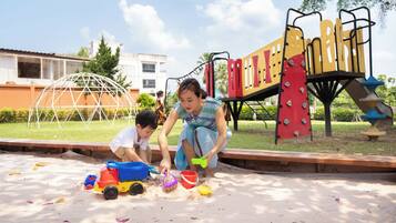 A playground with sand play area, climbing structures, and a dome-shaped shelter.