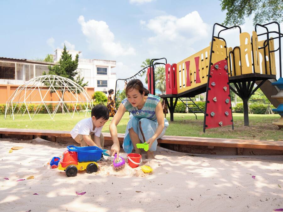 A playground with sand play area, climbing structures, and a dome-shaped shelter.