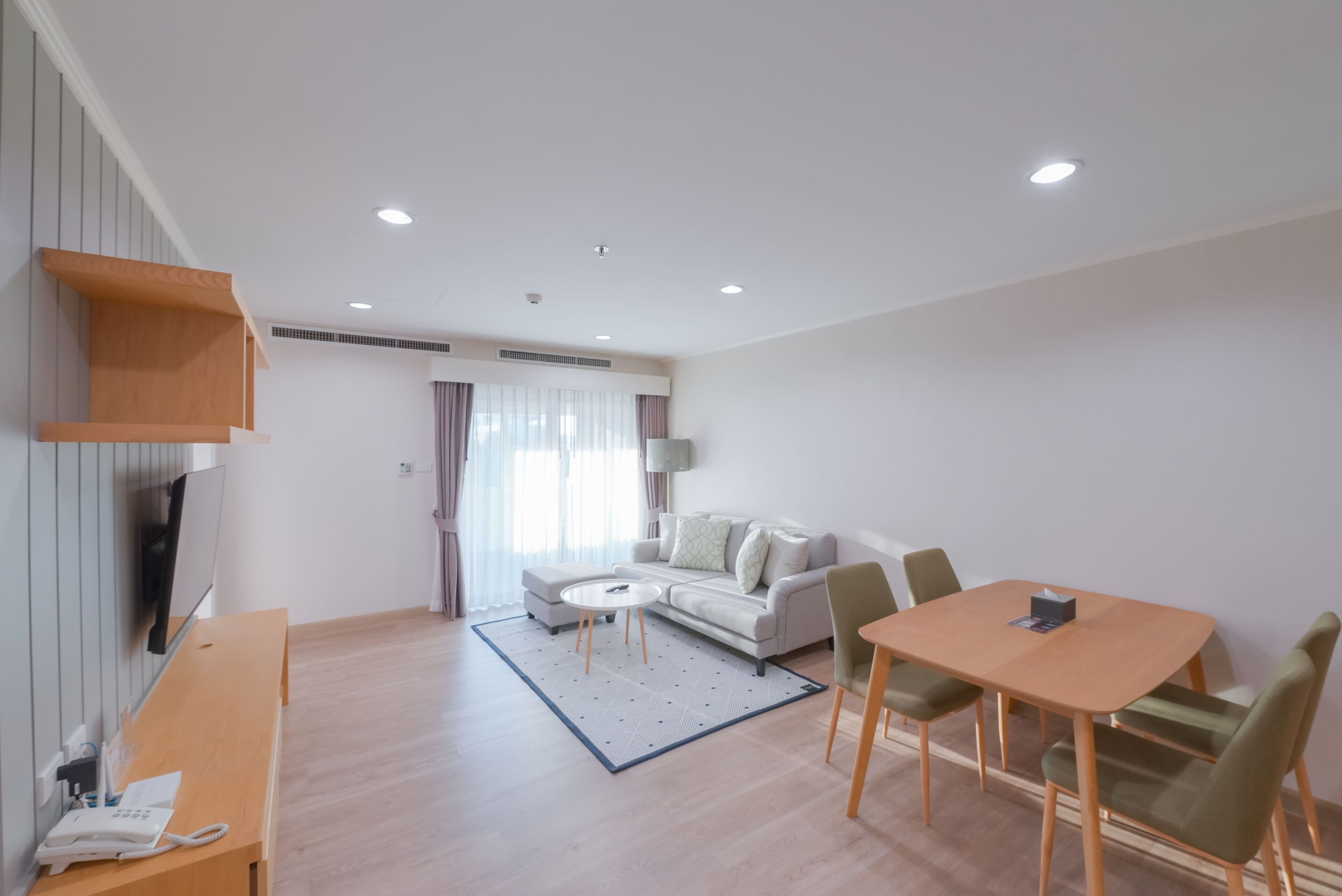 A modern living room with a sofa, a coffee table, and a dining area with chairs and a table.