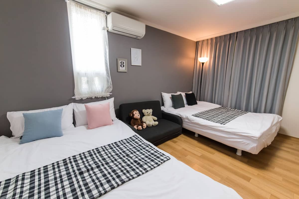 A hotel room with two beds, a sofa, and a small table.