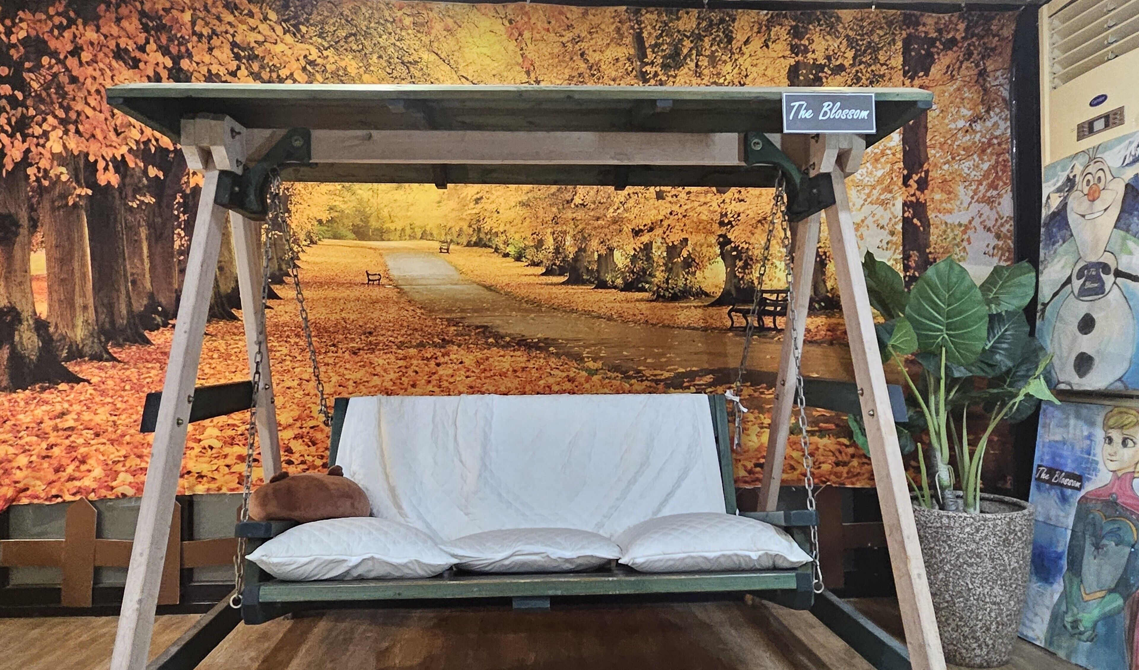 A swing bed with a view of a park with autumn leaves.