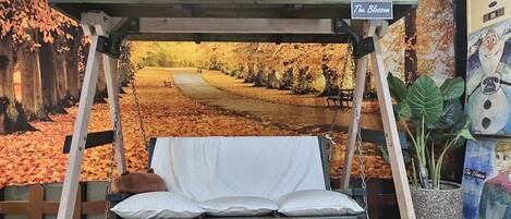 A swing bed with a view of a park with autumn leaves.