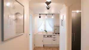 A modern kitchen with white cabinets, a dishwasher, and a refrigerator. - The Blossom Yeonnam Guesthouse (Seoul)