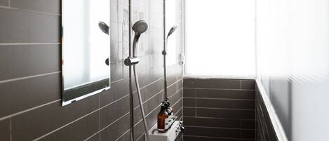 Un baño moderno con ducha, espejo y dispensador de jabón.