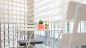 A balcony with a white table, two potted plants, and a cushioned bench. - The Blossom Yeonnam Guesthouse (Seoul)