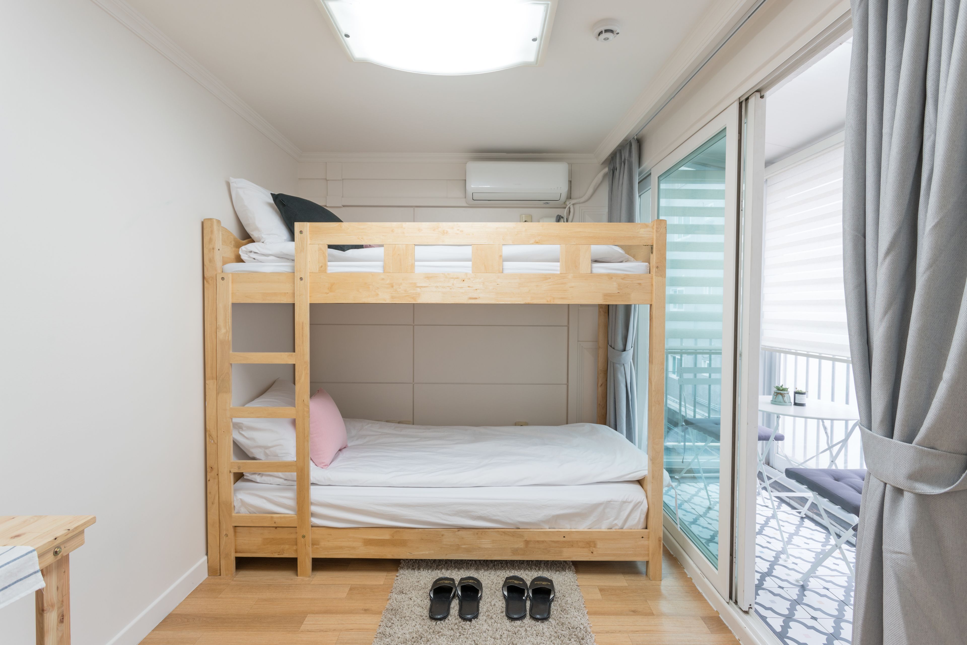 A bunk bed room with a skylight, a window with curtains, and a balcony with a railing.