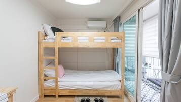 A bunk bed room with a skylight, a window with curtains, and a balcony with a railing.
