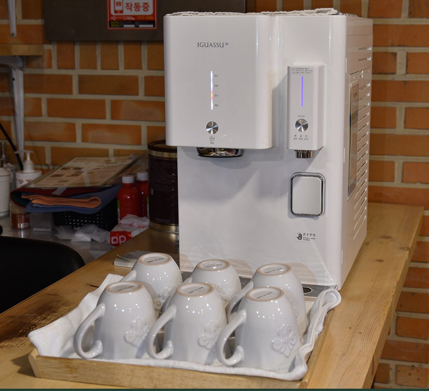 A coffee machine with a tray of white ceramic cups in front of it.