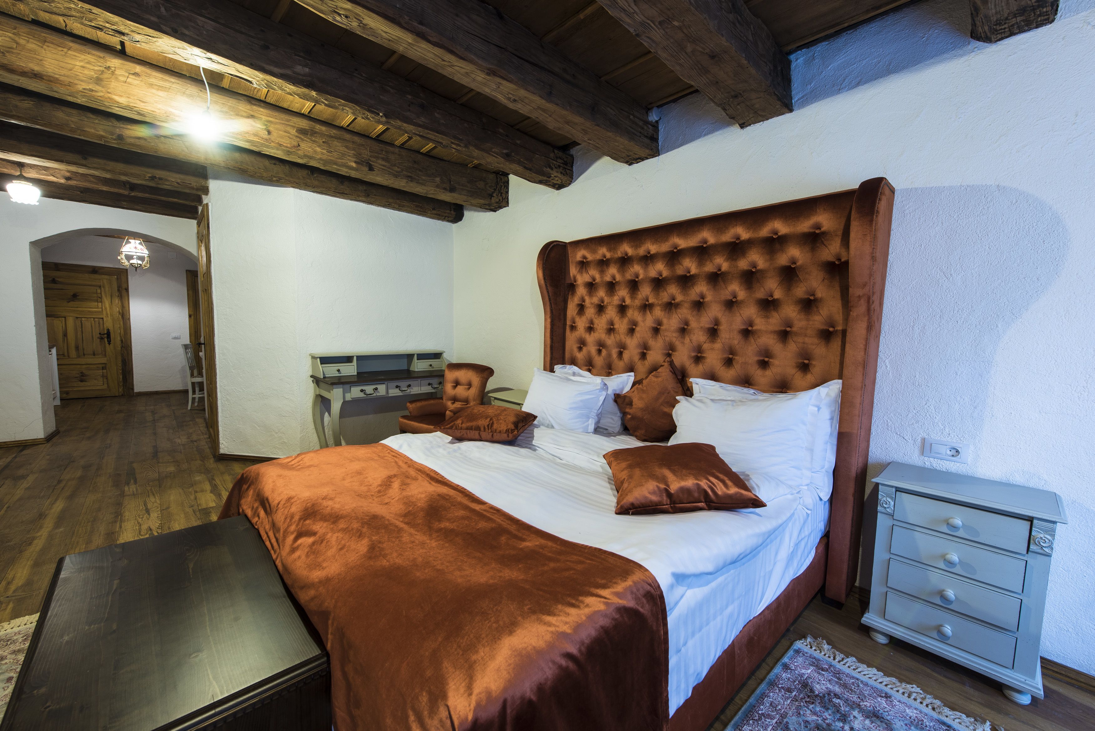 A bedroom with a large bed, wooden headboard, and a nightstand.