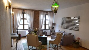 Uma sala de estar aconchegante com piso de madeira, uma luminária pendente verde e uma obra de arte na parede.