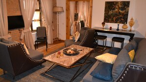 Uma sala de estar com sofá, poltronas, mesa de centro e televisão.