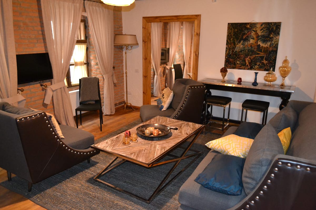 A living room with a sofa, armchairs, a coffee table, and a TV.