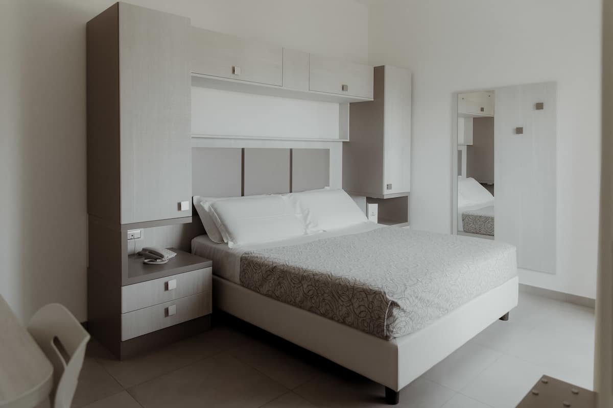 A modern bedroom with a bed, nightstands, a desk, and built-in cabinets.