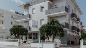 A multi-story hotel with balconies, a sign indicating a restaurant, and palm trees in the foreground. - Hotel Caravel (Vasto)