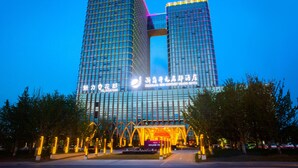 Un hotel moderno con fachada de vidrio destacada y señalización iluminada.