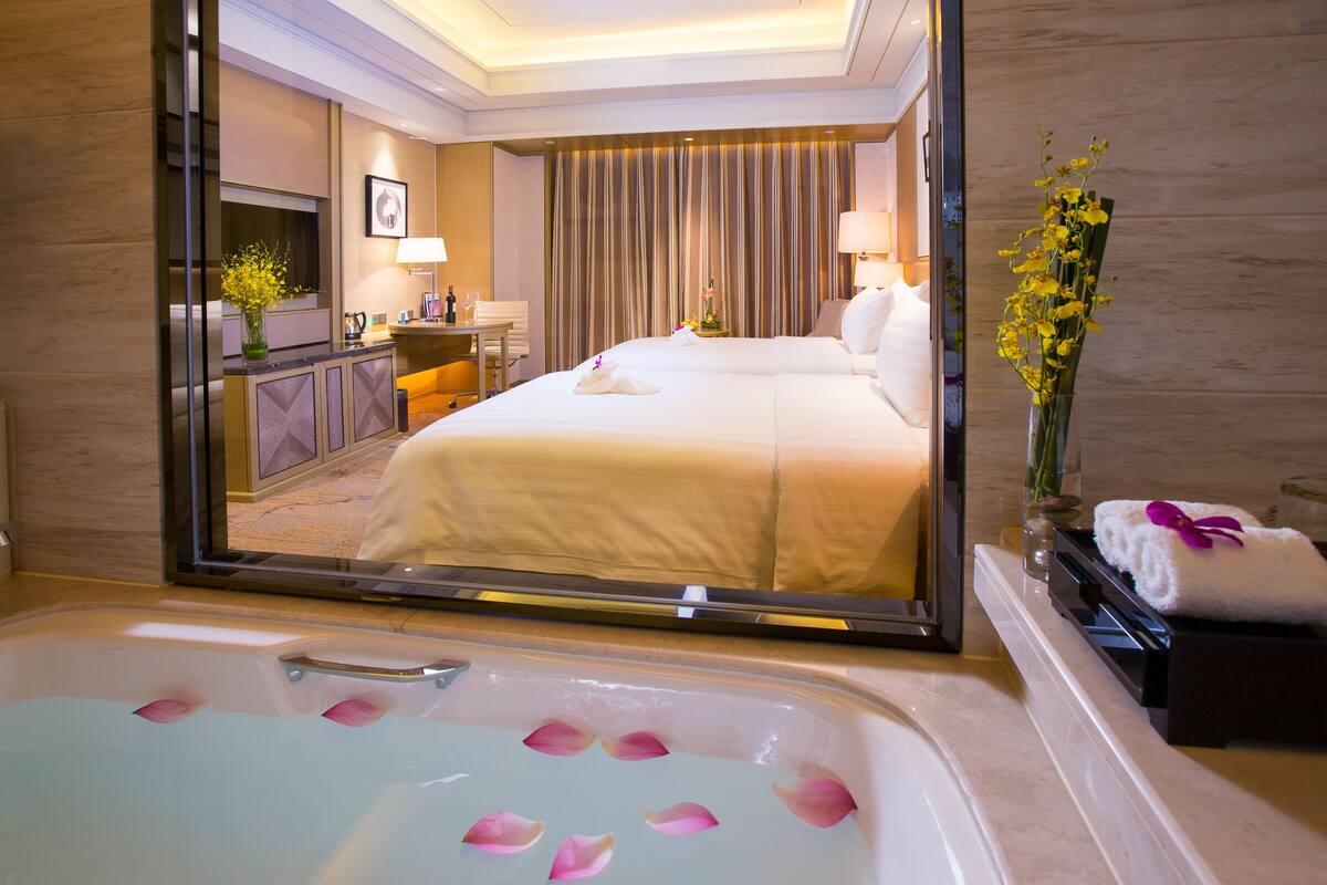 Ein Hotelzimmer mit einem großen Bett, einem Badezimmer mit einer Badewanne und einem Schreibtisch mit Stuhl.