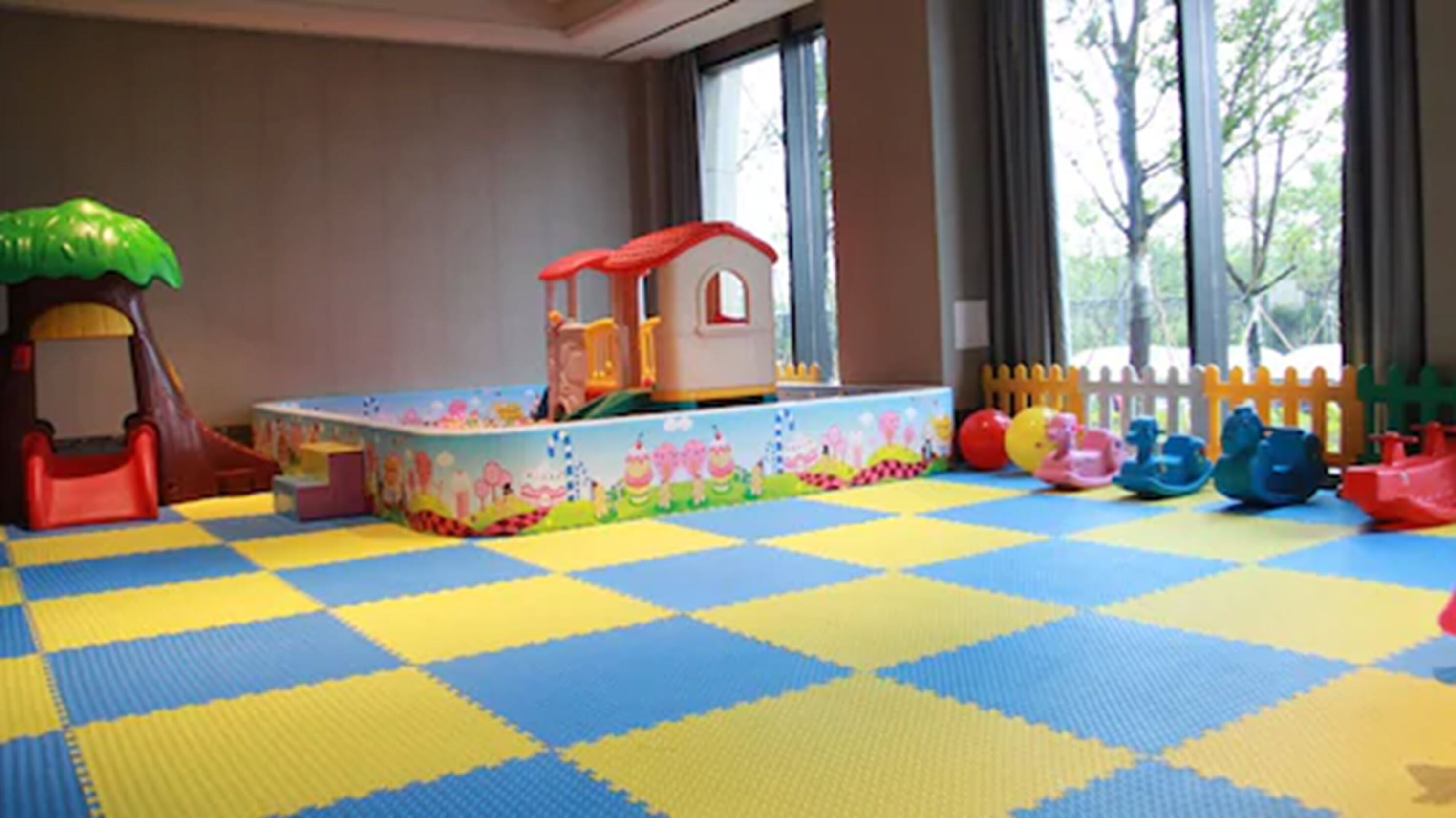 A play area with a colorful play mat, a small playhouse, and various toys.