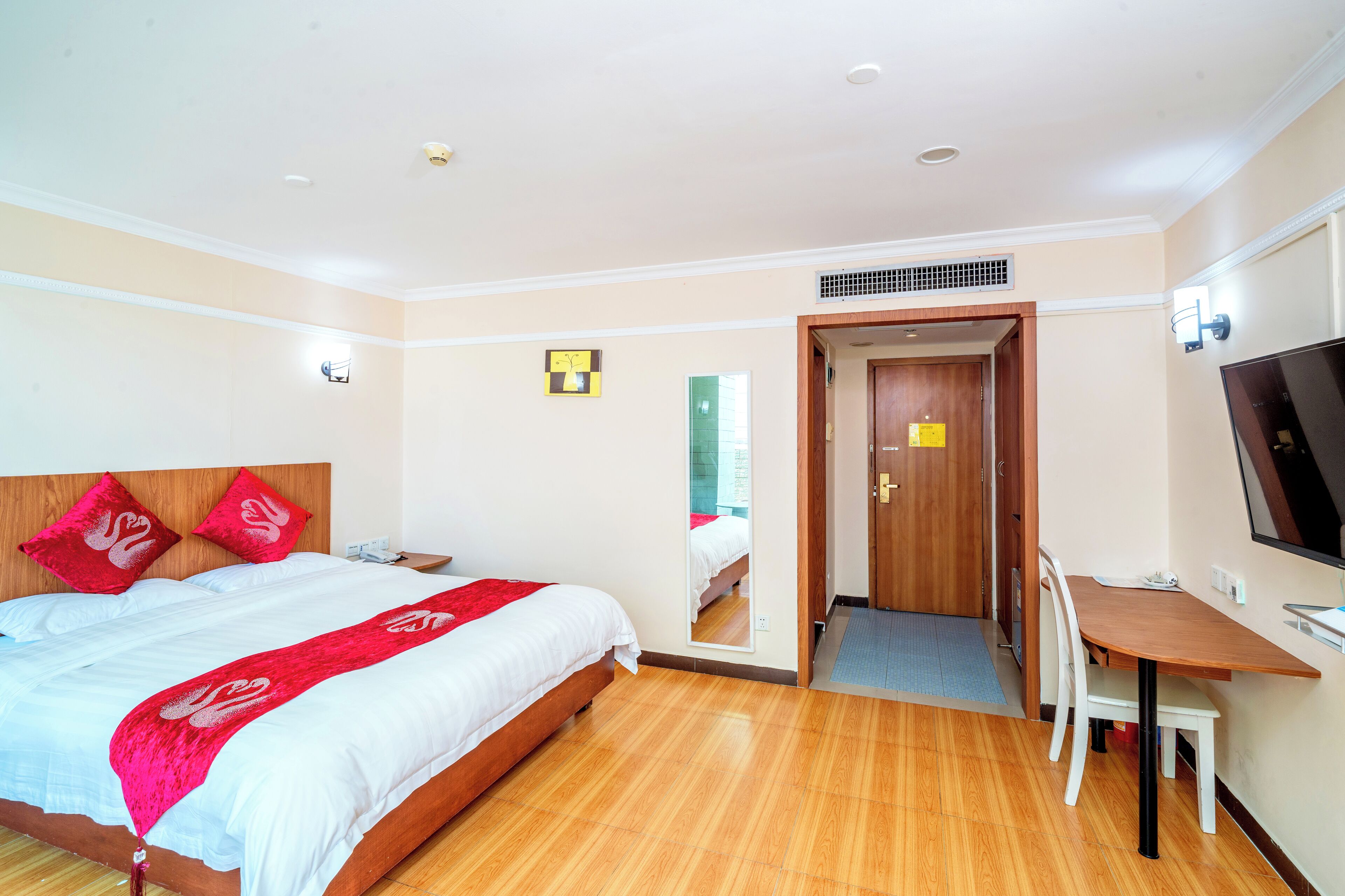 Una habitación de hotel con cama, escritorio, silla y televisión.