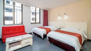 Ein Hotelzimmer mit zwei Betten, einem roten Sofa und einem kleinen Tisch.