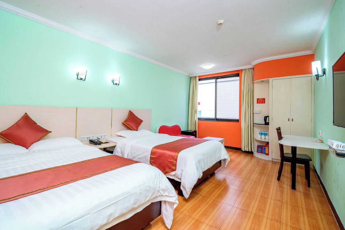 Une chambre d’hôtel avec deux lits, un bureau, une chaise, une télévision et une armoire.