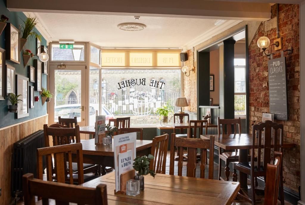 A restaurant interior with wooden tables and chairs, a menu stand, and a view of the street outside.