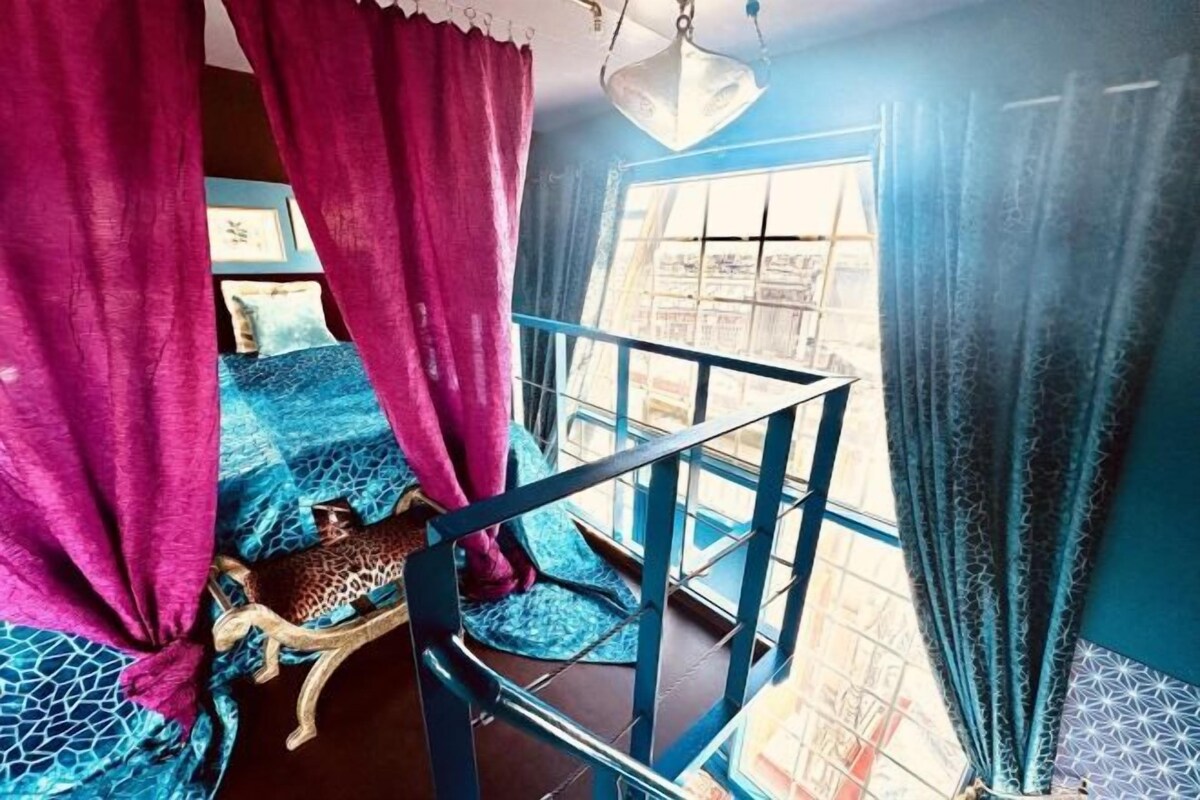 A room with a bed, a leopard print pillow, and a window with curtains.