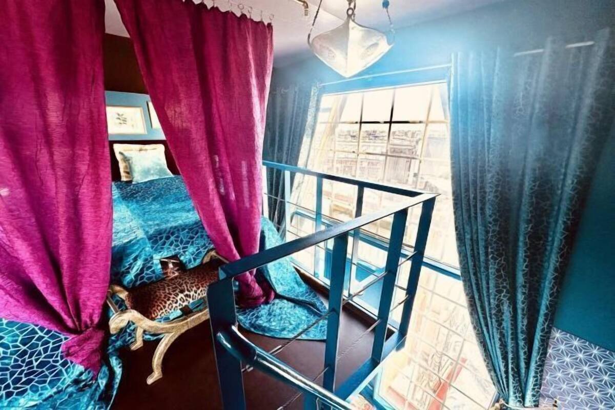 Een kamer met een bed, een kussen met luipaardprint en een raam met gordijnen.