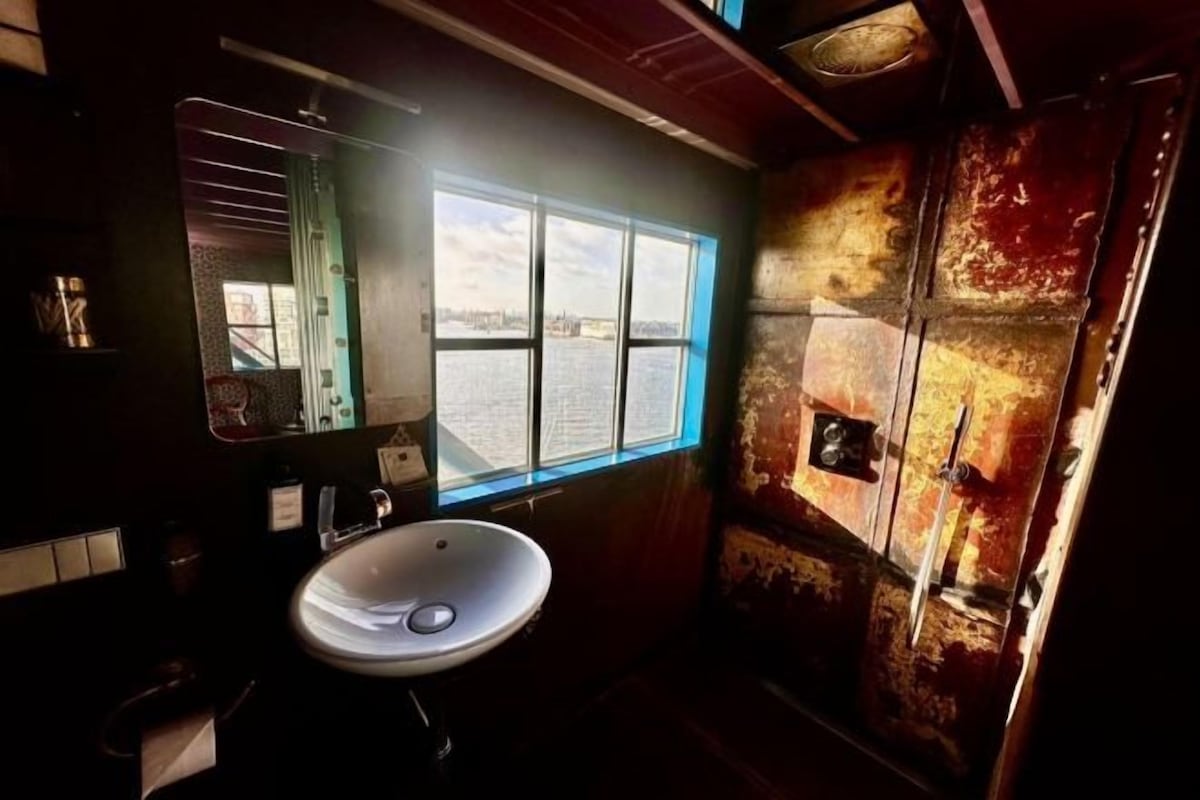 A bathroom with a sink, mirror, and window with a view of a body of water.