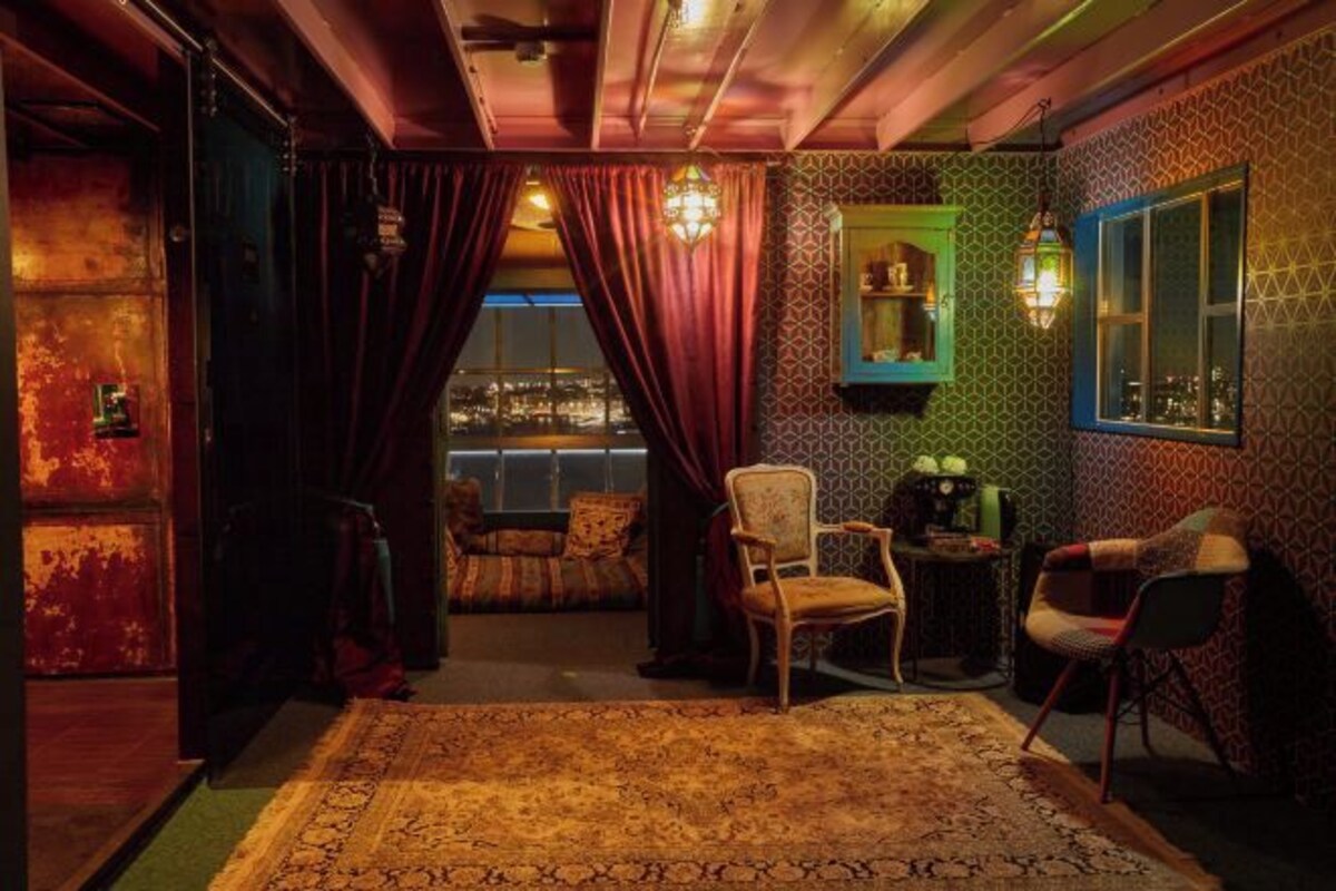 A room with a patterned wall, a view through a window, and a chair.
