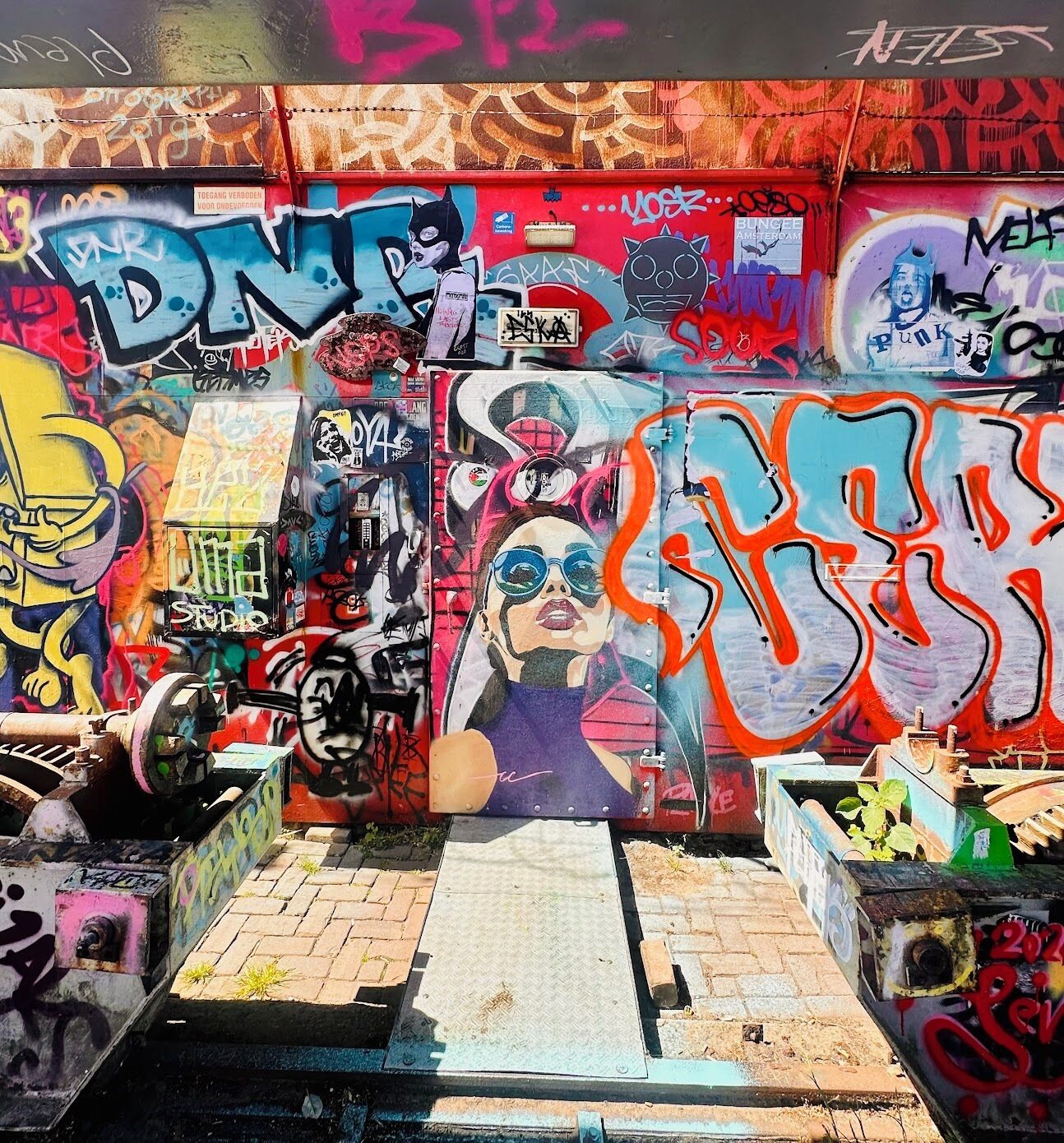 Eine mit Graffiti besprühte Wand mit einem großen, farbenfrohen Wandgemälde.