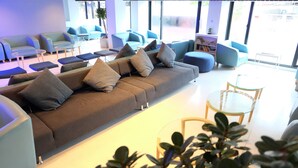 Un espace de détente moderne, doté d’un grand canapé d’angle, de plusieurs options d’assises et d’une table basse en verre.