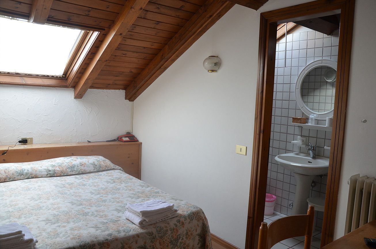 A bedroom with a skylight, a bed with a floral bedspread, a wooden headboard, and a small bedside table with a lamp.
