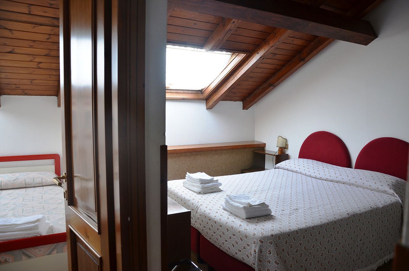 Una camera da letto con una finestra a lucernario, un letto con testiere rosse e un comodino con una lampada.