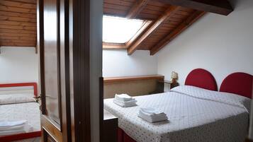 Una camera da letto con una finestra a lucernario, un letto con testiere rosse e un comodino con una lampada.