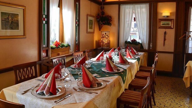 Comedor con una mesa larga dispuesta para varios invitados, con elegantes ajustes de mesa y cálida decoración de madera.