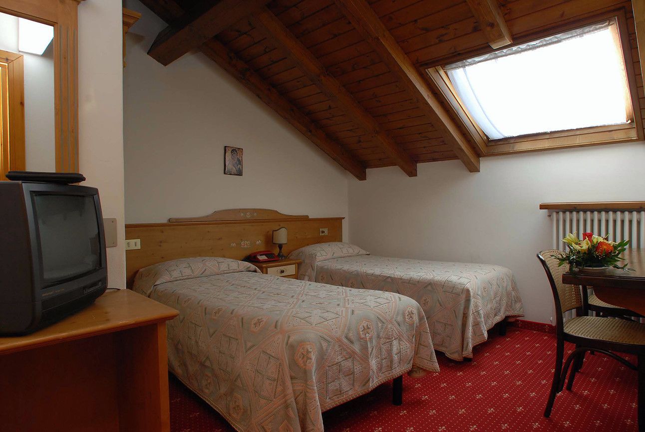 Une chambre avec deux lits, un téléviseur posé sur un meuble, une table avec une chaise et une fenêtre donnant sur un paysage agréable.